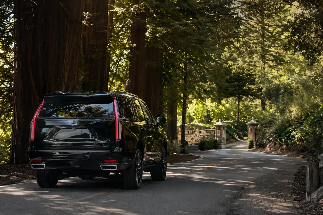 Luxury SUV on a wooded Woodside road beneath mature redwoods